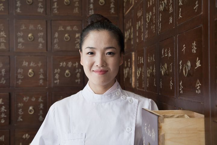 Portrait of doctor in front of a traditional Chinese medicine cabinet