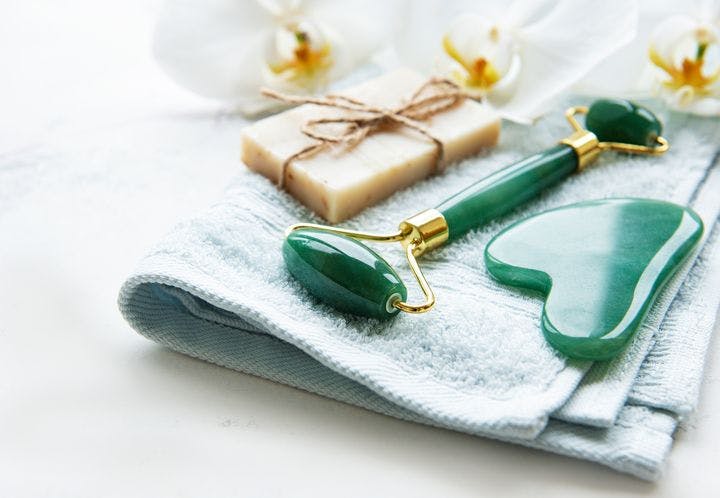 Different gua sha tools and soap on a face towel