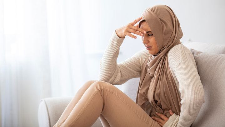 Sick Muslim girl in hijab experiencing lower abdominal pain.