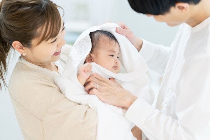Asian couple drying off baby with towel after bath
