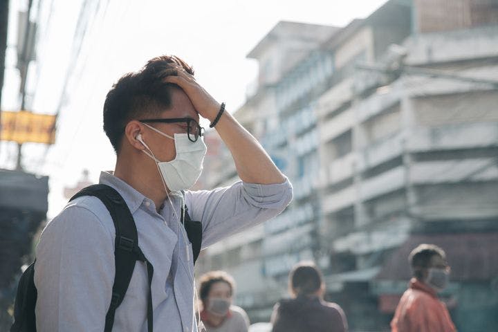 A man wearing a mask and earphones while crossing the street