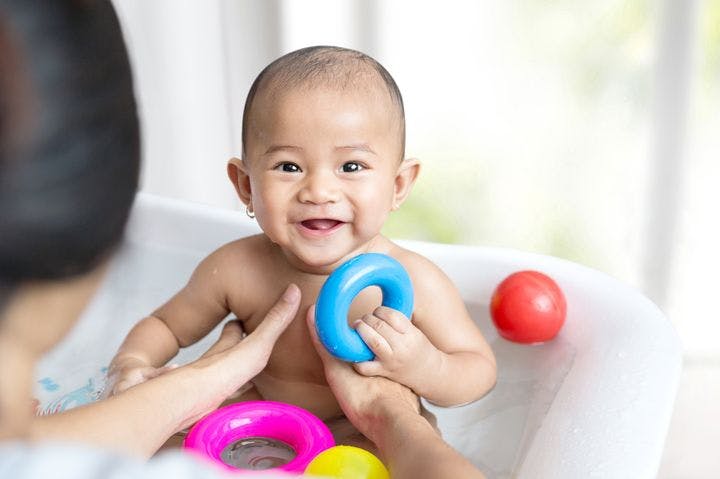 A baby playing with her toys during baby bath time in the tub