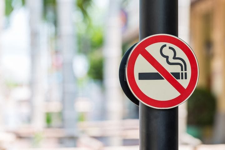 A “No Smoking” signage on both sides of a black-coloured pillar outdoors