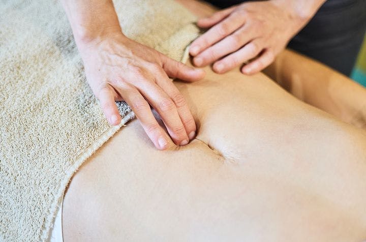 A therapist massaging a spot underneath the navel to support pelvic floor muscles