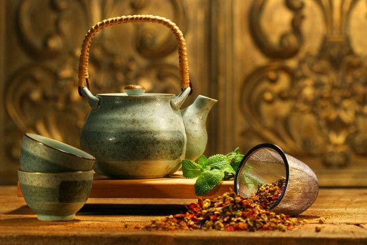 Teapot, cups, and Chinese herbs in a strainer on the table