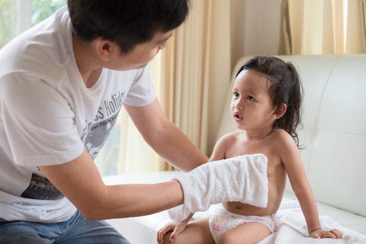 Man wiping a child’s body with a white cloth