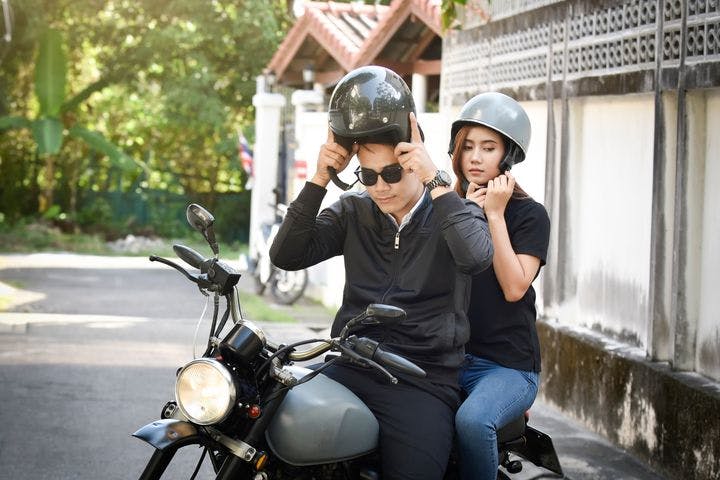 A man and woman riding a motorcycle, wearing helmets