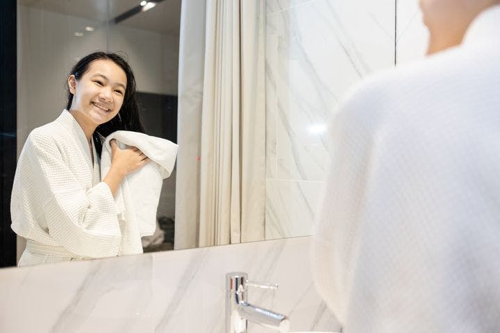 Woman in bathrobe drying her wet hair using a white towel