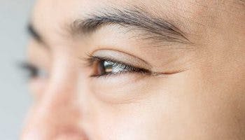 Closeup of a woman’s smiling face showing faint Crow’s Feet in the outer corner of her eye.