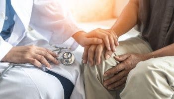 Photo of a doctor holding the hand of an elderly Parkinson's disease patient