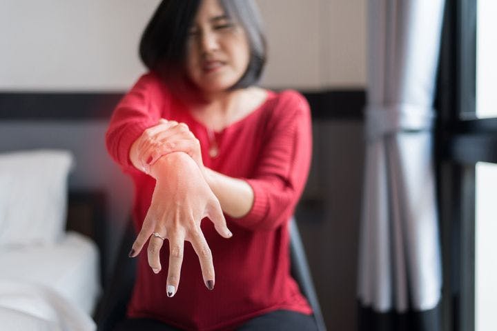 A woman holding her wrist indicating she might have Parkinson's disease.