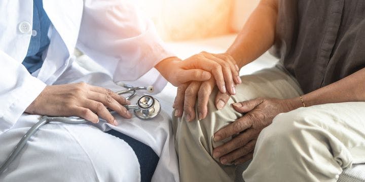 Photo of a doctor holding the hand of an elderly Parkinson's disease patient