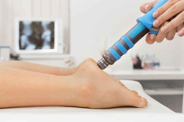 Healthcare provider administering shockwave therapy to a patient’s left heel.