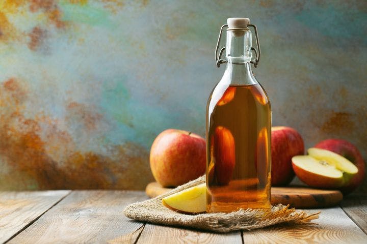 A bottle of apple cider vinegar with apples