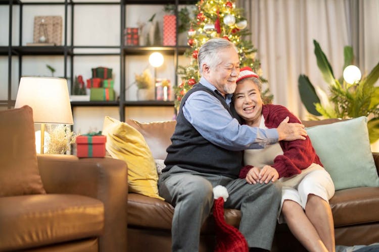 Senior asian retired couple enjoy hug and talking conversation together on sofa