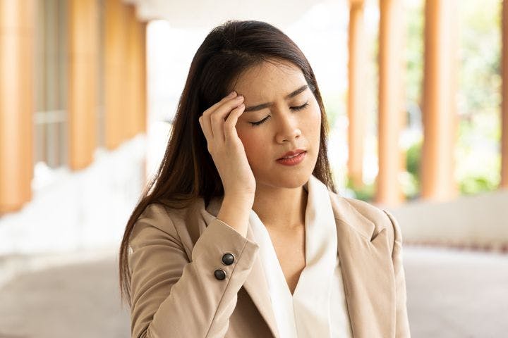 Woman holds her head while feeling dizzy.