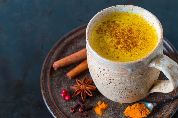 A cup of golden milk made with turmeric, cinnamon, and star anise.