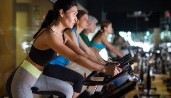 Group of women performing a routine together on spinning bikes. 