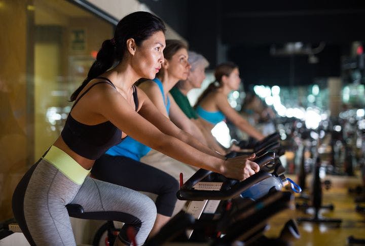 Group of women performing a routine together on spinning bikes. 