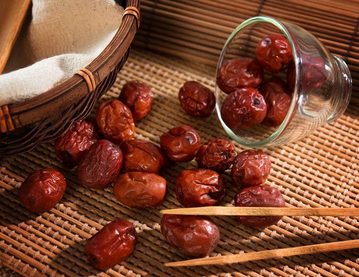 Dried red dates or Chinese jujube spilled onto a straw mat. 