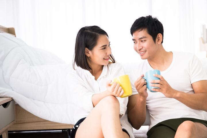 Young couple drinking tea together in the bedroom