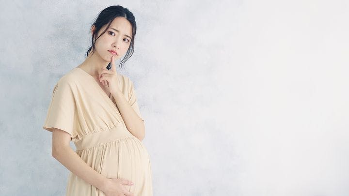 Young pregnant woman with a worried expression against a white background.