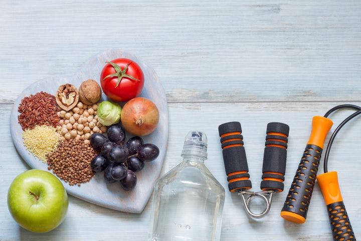 A flat-lay of healthy foods on a platter and gym equipment.