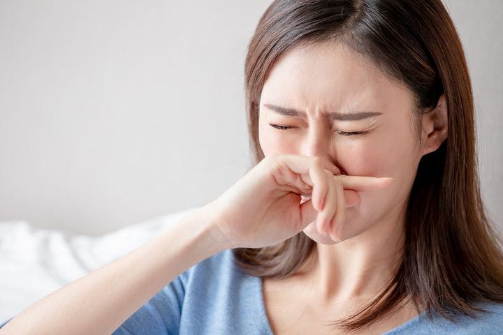 Woman using her right hand to cover her nose while closing her eyes