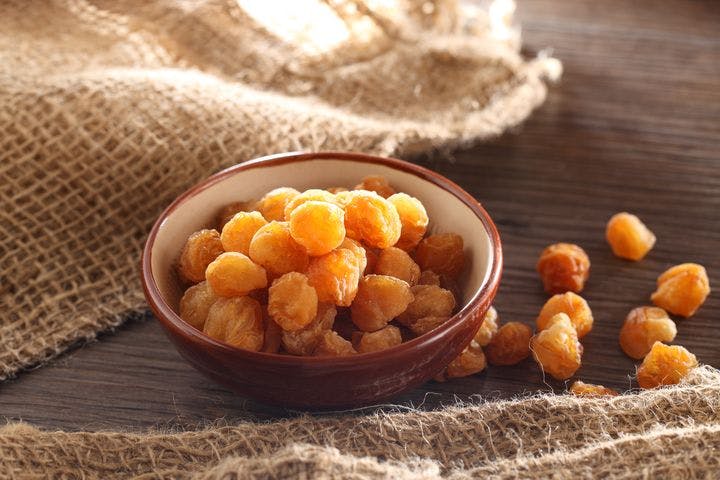 A bowl of dried longan on a wooden surface.  