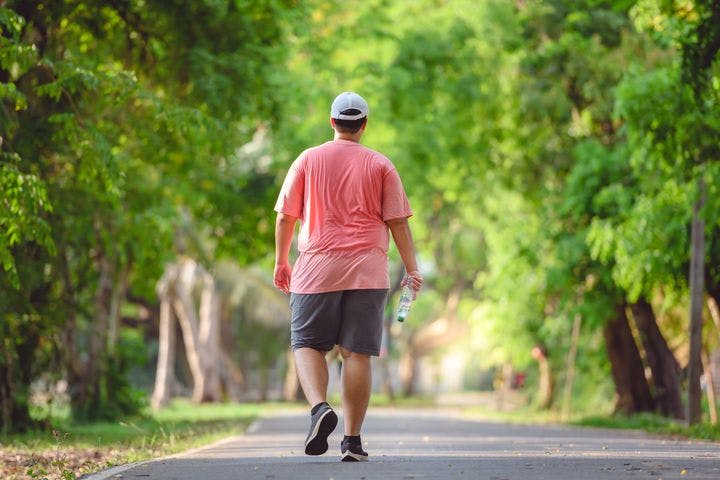Man walks in a park, holding a water bottle.