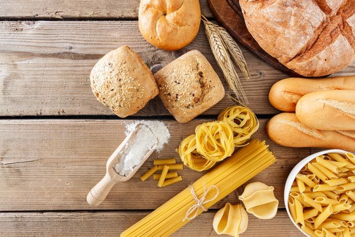 Close-up display of an assortment of pasta and bread on a wooden table.