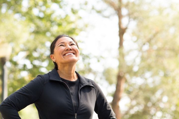 A woman smiling gleefully as she looks up while standing outdoors. 