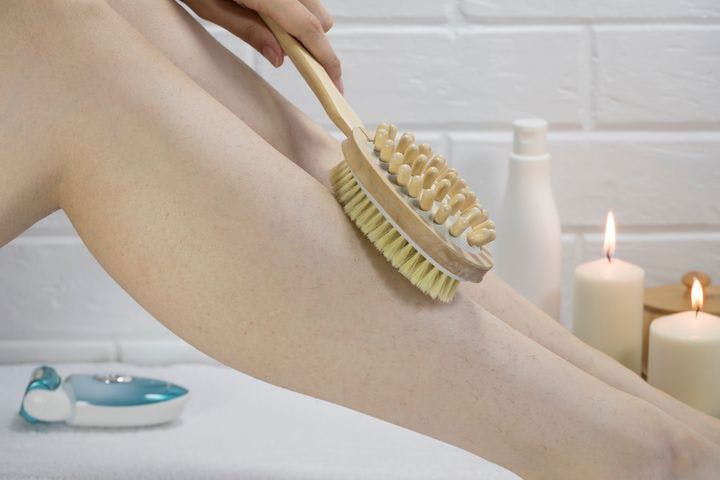 Exfoliation with a natural bristle brush, dry brush massage on legs