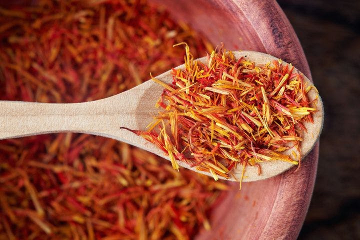 Dried safflower petals in a wooden spoon and bowl.