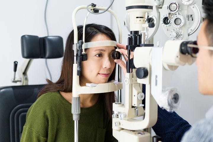 A woman undergoing a vision test guided by an optometrist using a tonometer.