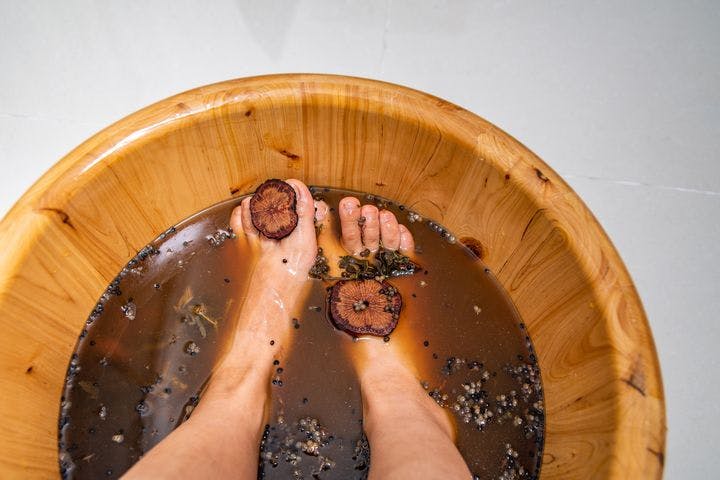 A woman soaking her feet in a Chinese medicine foot bath