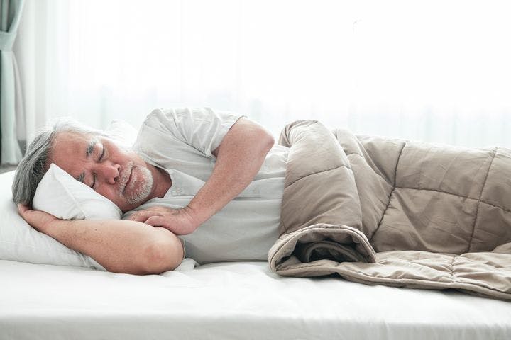 Older man lying in bed sleeping.