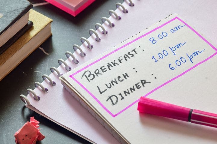 Notebook with “breakfast”, “lunch”, and “dinner” and mealtimes written.
