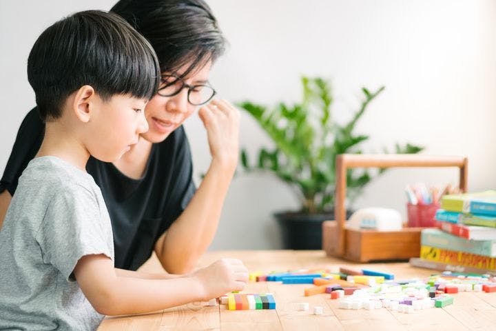 A mother teaching her son using colourful blocks.