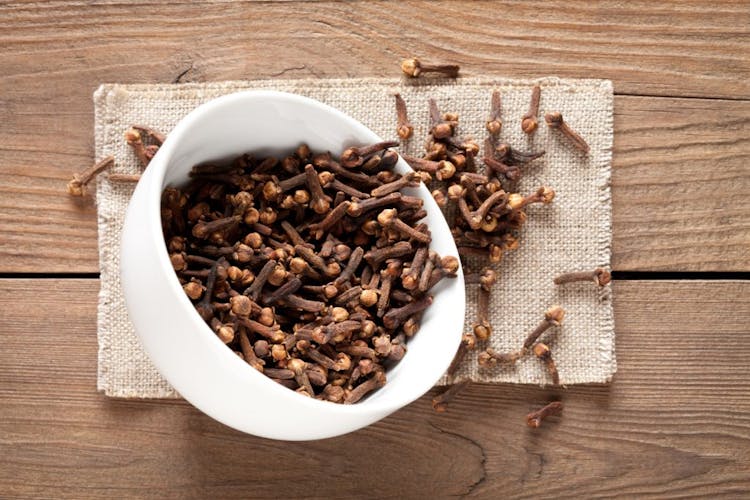 Close up of cloves in cup on wooden table