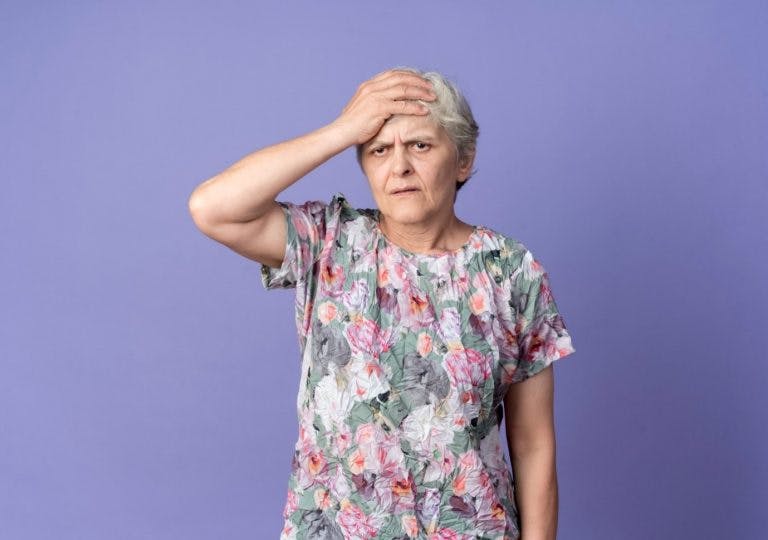Unhappy senior woman placing her hand on her forehead