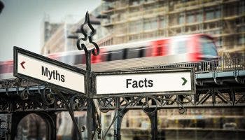 A street sign pointing in two directions, saying ‘Myths’ and ‘Facts’