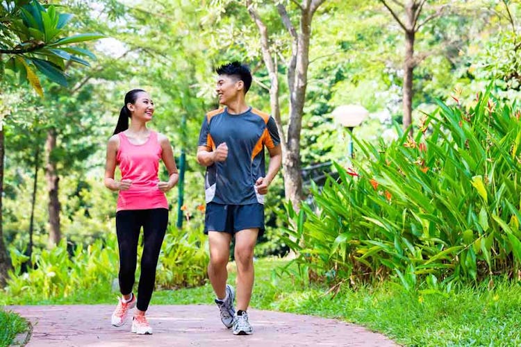 An Asian man and an Asian woman jog in a park