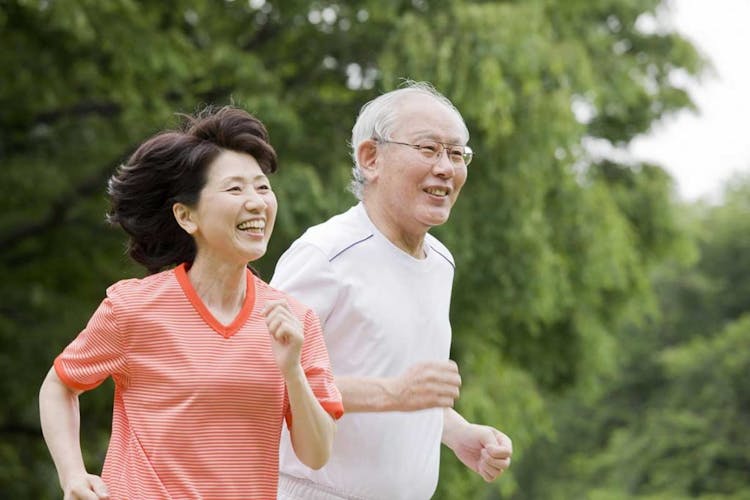 A senior couple jog together in a park happily