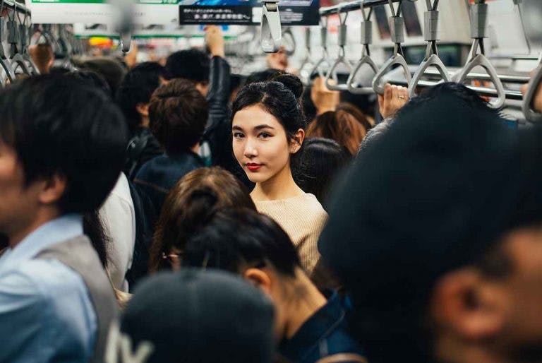 Young Asian woman standing in the middle of a packed train