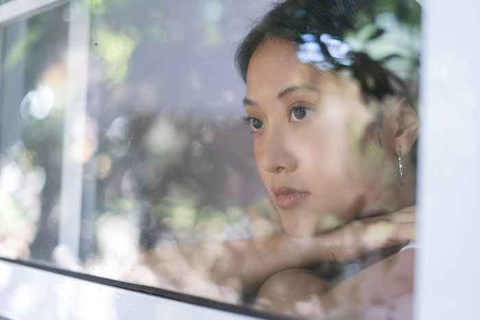 A close-up of a woman as she looks out the window