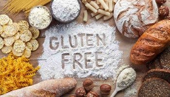 Top view of gluten-free food, including pasta, bread, snacks, and flour on wooden background