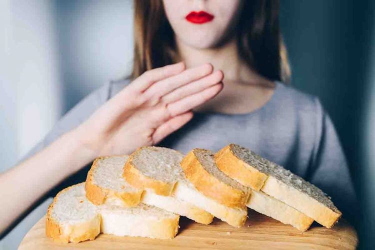 A girl putting out her hand in front of slices of white bread