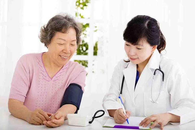 An Asian doctor checks an old Asian woman’s blood pressure