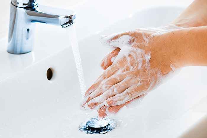 Woman rinsing her lather-filled hands under clean tap water